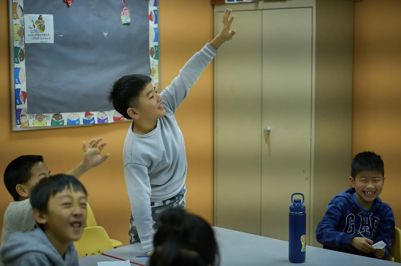 A young boy raising his hand in a classroom at WCEC in Hockessin, DE
